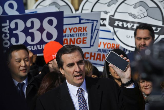 In November, New York State Sen. Michael Gianaris, center, calls on supporters to remove the Amazon app from their phones and boycott the compony, as he address a coalition rally and press conference